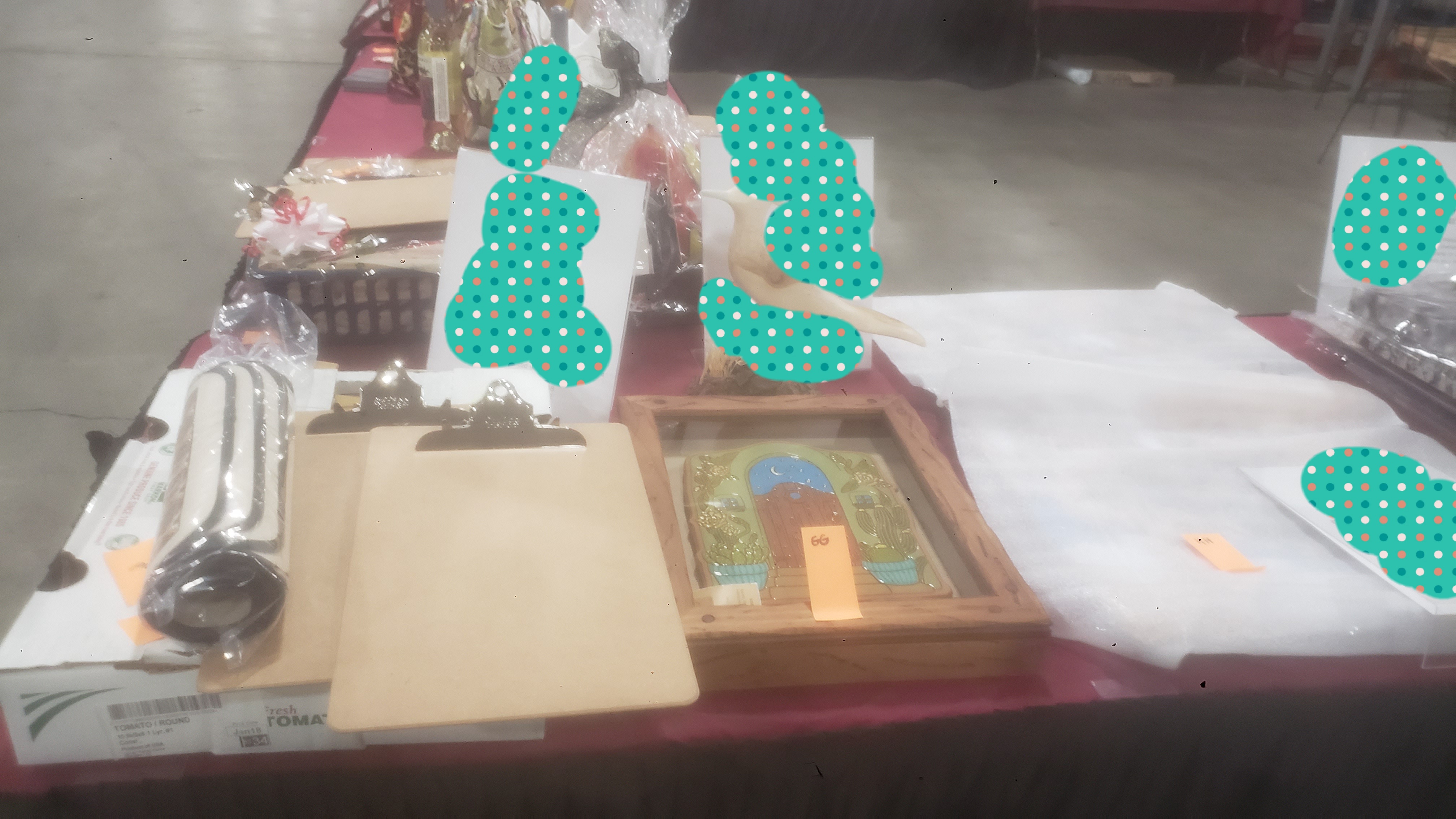 Silent auction items such as art pieces on a table with signs.
